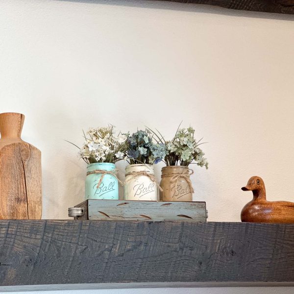 Schaefbauer home on Munson Lake living room shelf with decorative pastel vases with dried flowers between a wooden vase and a wooden duck