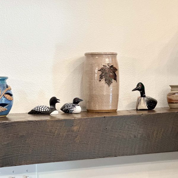 Schaefbauer home on Munson Lake living room shelf featuring a decorative ceramic vase between wooden loons