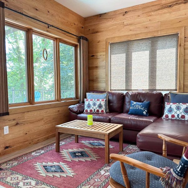 Schaefbauer home on Munson Lake knotty pine sunroom/den with maroon leather sectional and coffee table