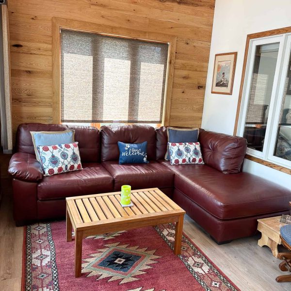 Schaefbauer home on Munson Lake knotty pine sunroom/den with maroon leather sectional and coffee table