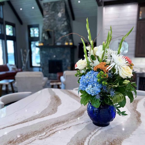 Spicer Home on Pelican Lake • marble island countertop with flowers • living room fireplace area in background