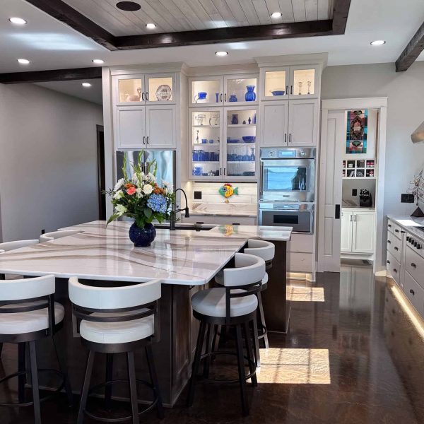 Spicer Home on Pelican Lake • marble island countertop with flowers • Island seating area with a view of refrigerator and oven in the background