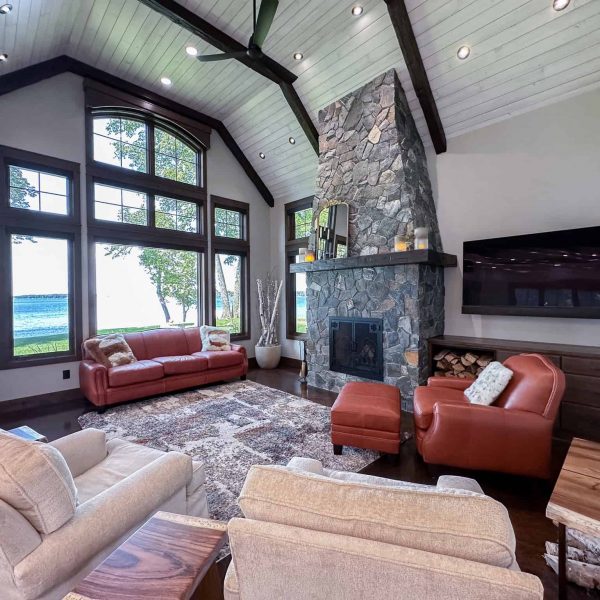Spicer Home on Pelican Lake • living room with large lakeside window and tall rock fireplace