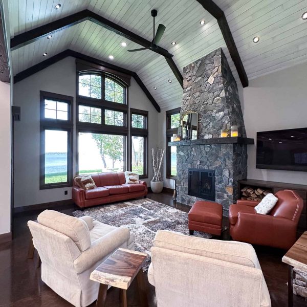 Spicer Home on Pelican Lake • living room with large lakeside window and tall rock fireplace
