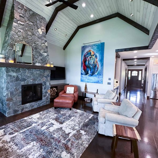 Spicer Home on Pelican Lake • Living room with a large painting of a bear near the tall rock fireplace