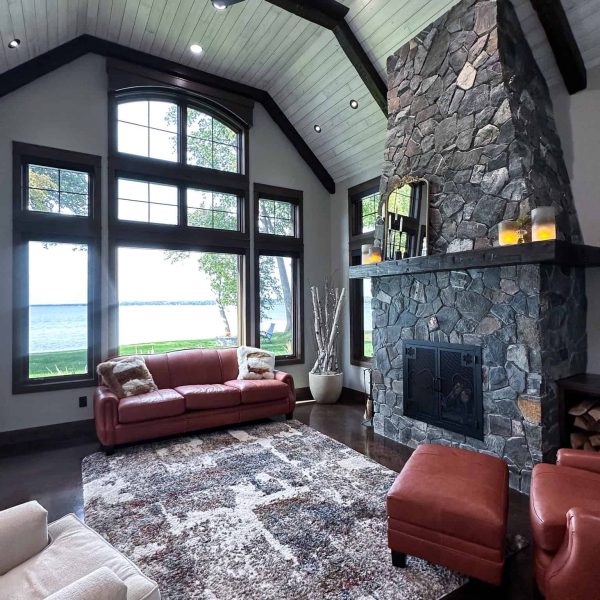 Spicer Home on Pelican Lake • living room with large lakeside window and tall rock fireplace
