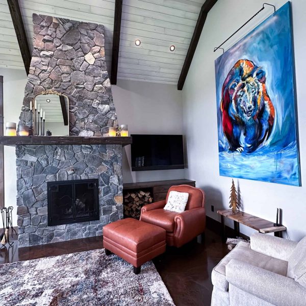 Spicer Home on Pelican Lake • Living room with a large painting of a bear near the tall rock fireplace