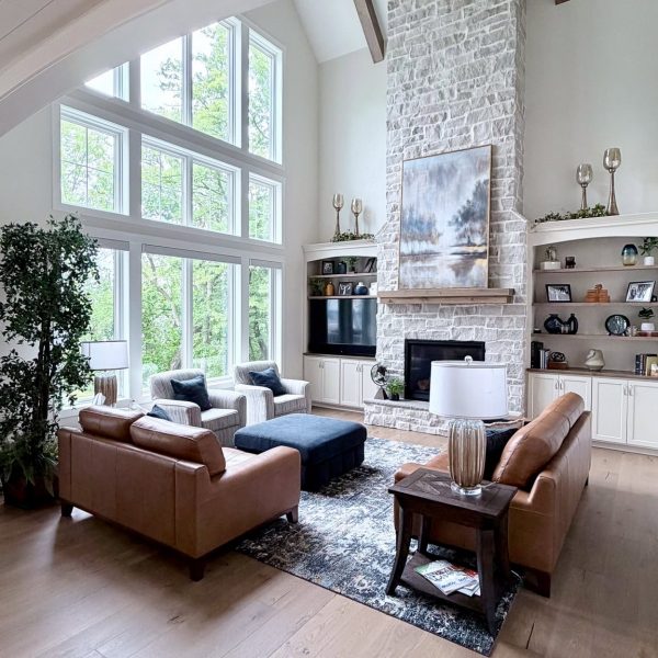 Elegant living room with large windows, stone fireplace, and modern furniture.