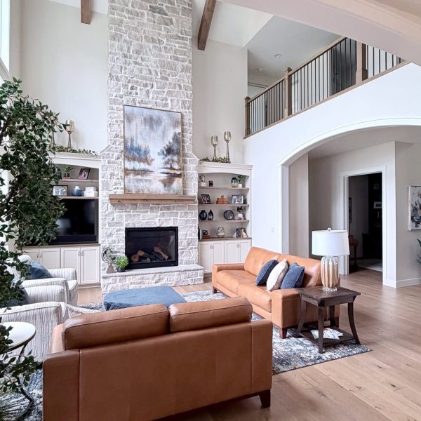 Spacious modern living room with fireplace, high ceilings, and large windows.