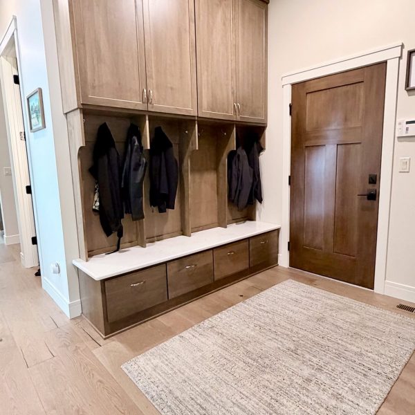 Modern mudroom with wooden cabinets, hooks, and storage bench by Briard Construction.