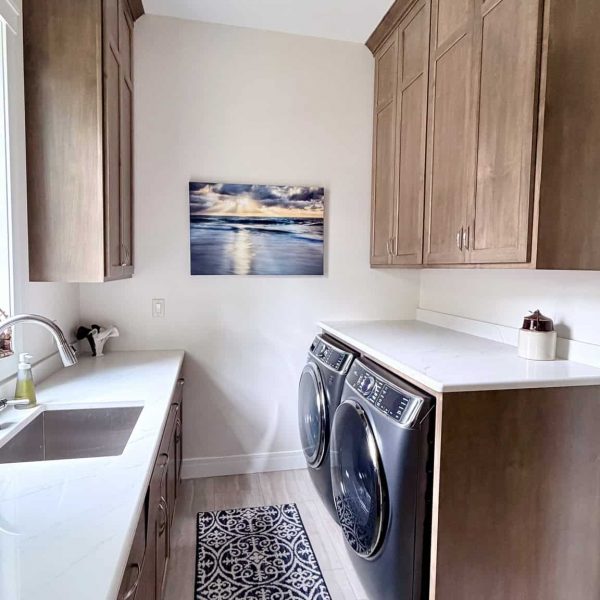 Clean and modern laundry room with wooden cabinets and washer-dryer units.