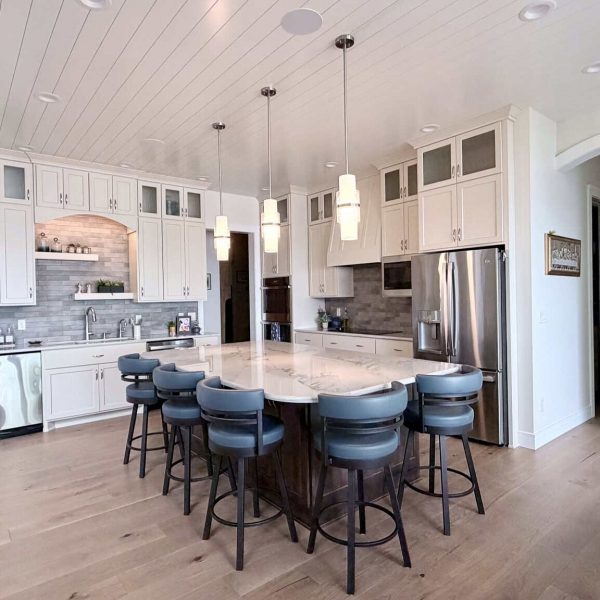 Spacious modern kitchen with island, white cabinets, and stainless steel appliances.