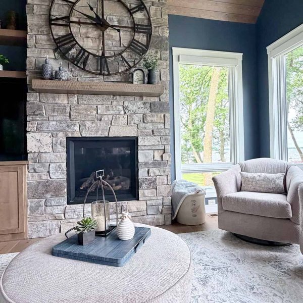 Cozy living room featuring a stone fireplace, large clock, and comfortable seating.