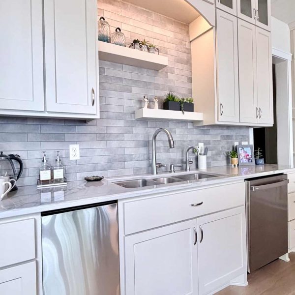 Contemporary white kitchen with gray backsplash and stainless steel appliances.