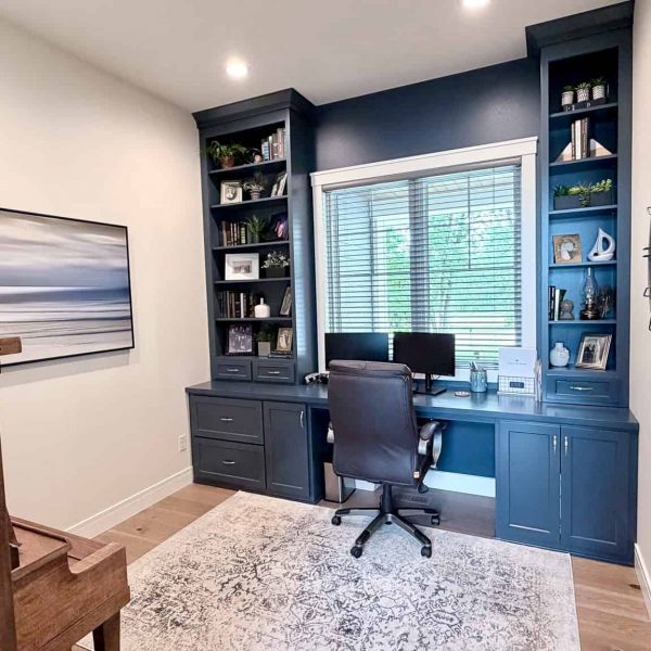 Modern home office with built-in blue shelves and desk by Briard Construction.