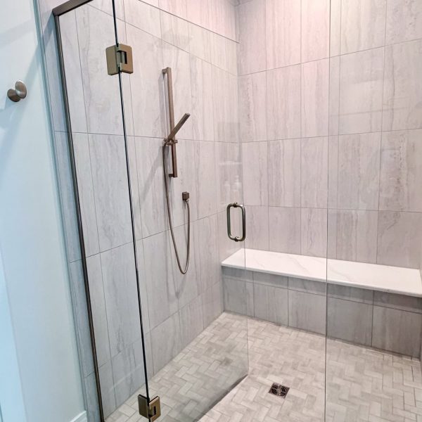 Contemporary walk-in glass shower with bench and rainfall showerhead.