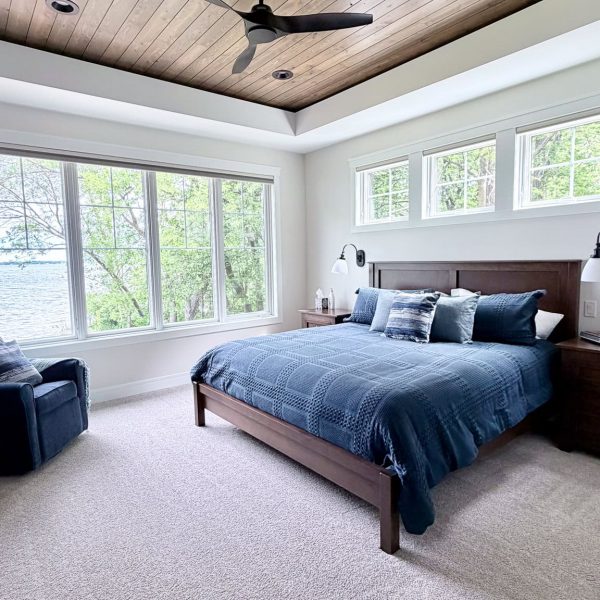 Spacious bedroom with wooden ceiling, large windows, and modern decor.