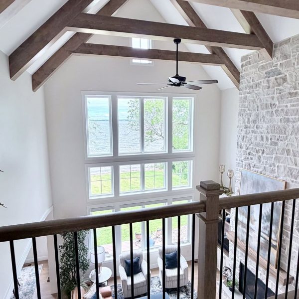 Spacious living room with vaulted ceilings, large windows, and a stone fireplace.