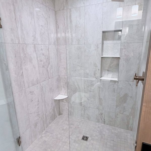 Contemporary walk-in glass shower with built-in shelves and rainfall showerhead.