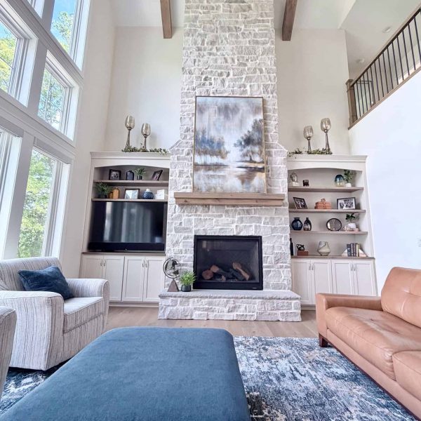 Spacious living room with a tall stone fireplace and large windows.
