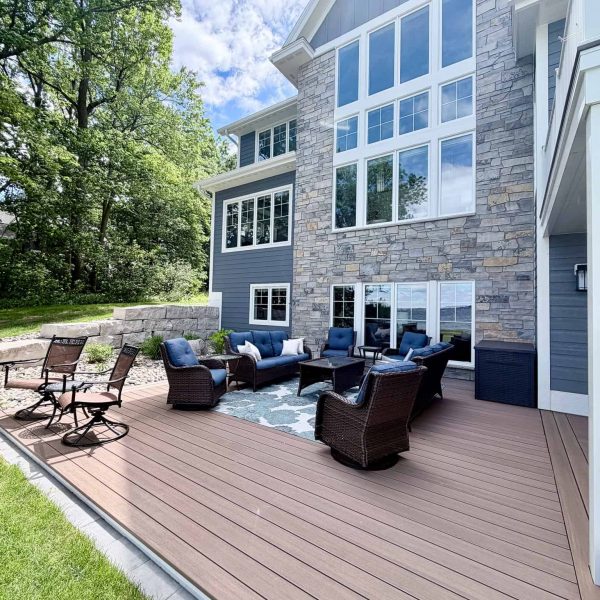 Modern house with large windows and outdoor deck with seating area.