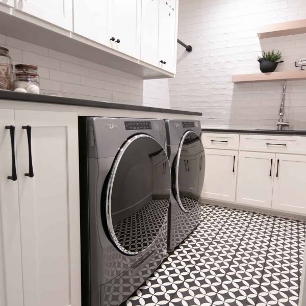 Zunich Home on Detroit Lake Laundry Room washer and dryer with black countertop, white cabinets, and shelving with bird pot with a leafy plant and an iron clean sign
